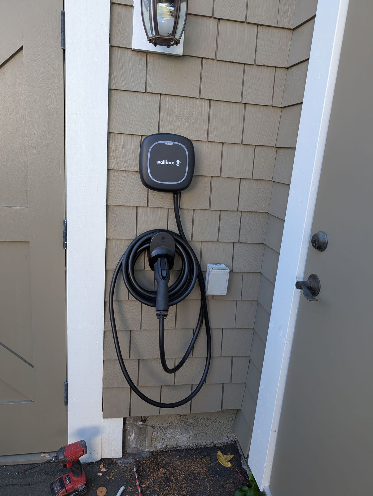 Wallbox EV charger installed beside a door with the cable neatly coiled
